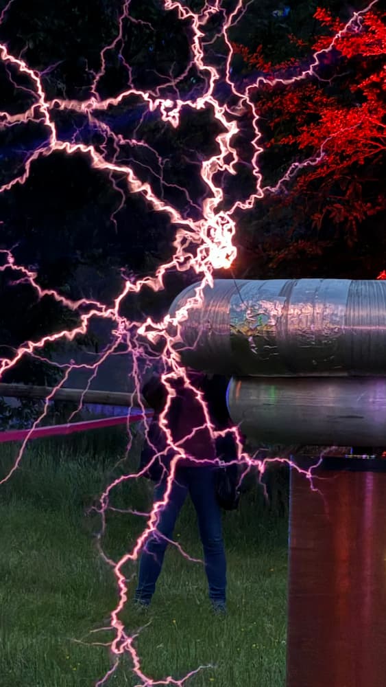 Close up photo of the top section of a Tesla coil with several strands of electricity coming off of it